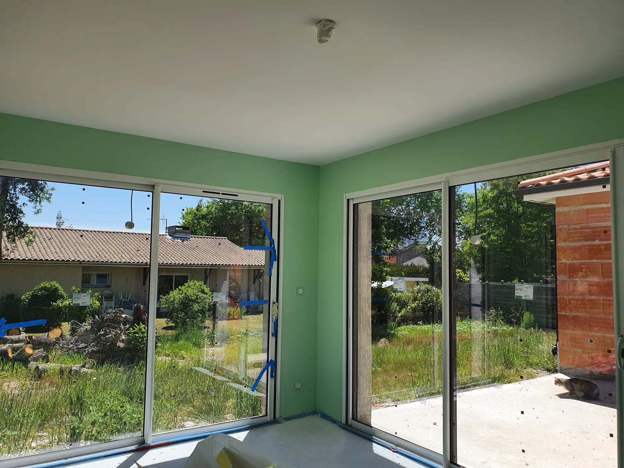Pièce repeinte en vert tendre avec plafond blanc, menuiseries protégées pendant le chantier