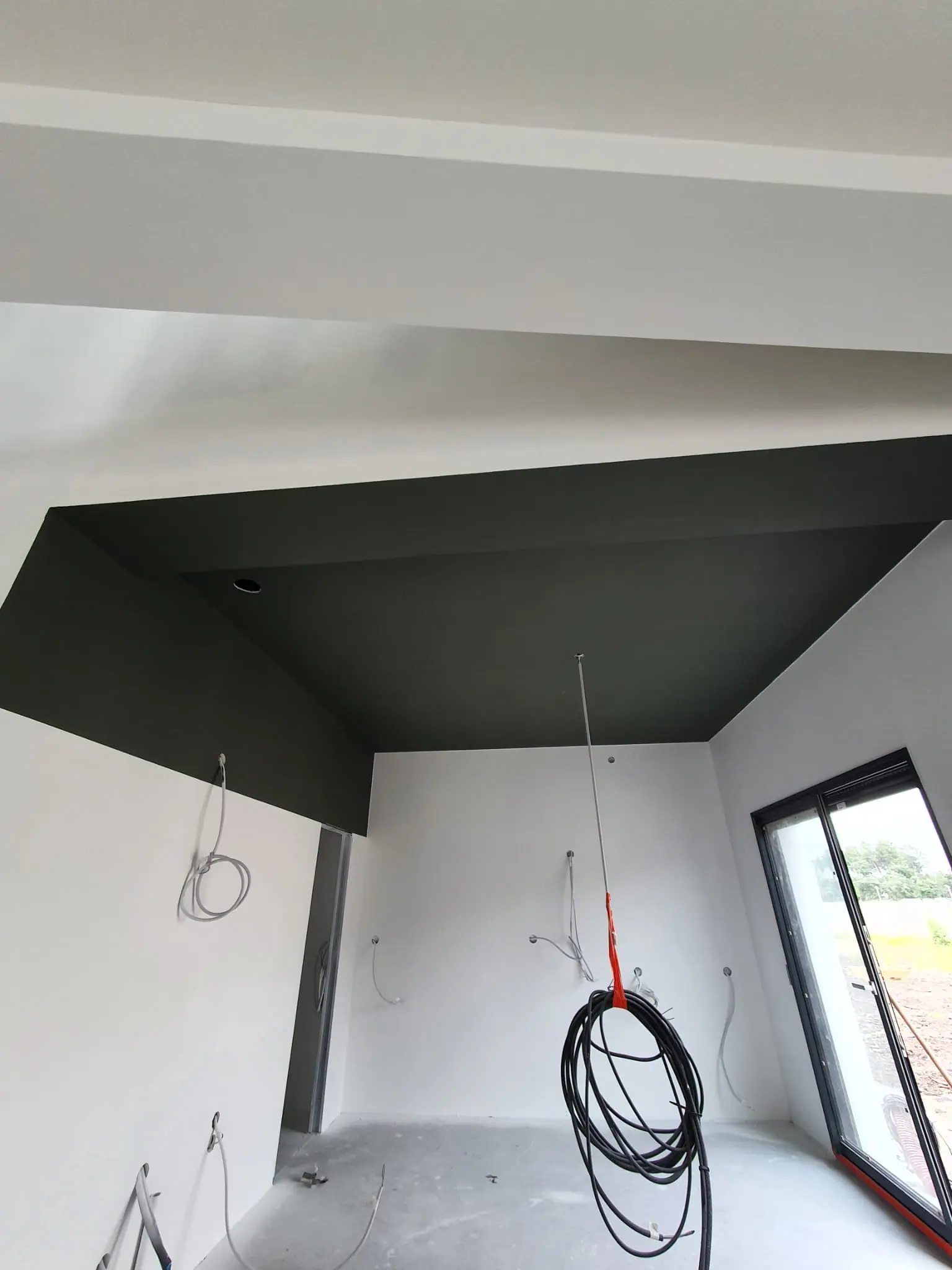 Maison neuve en finition : plafond en caisson vert profond et murs blancs, peints avant la pose des luminaires