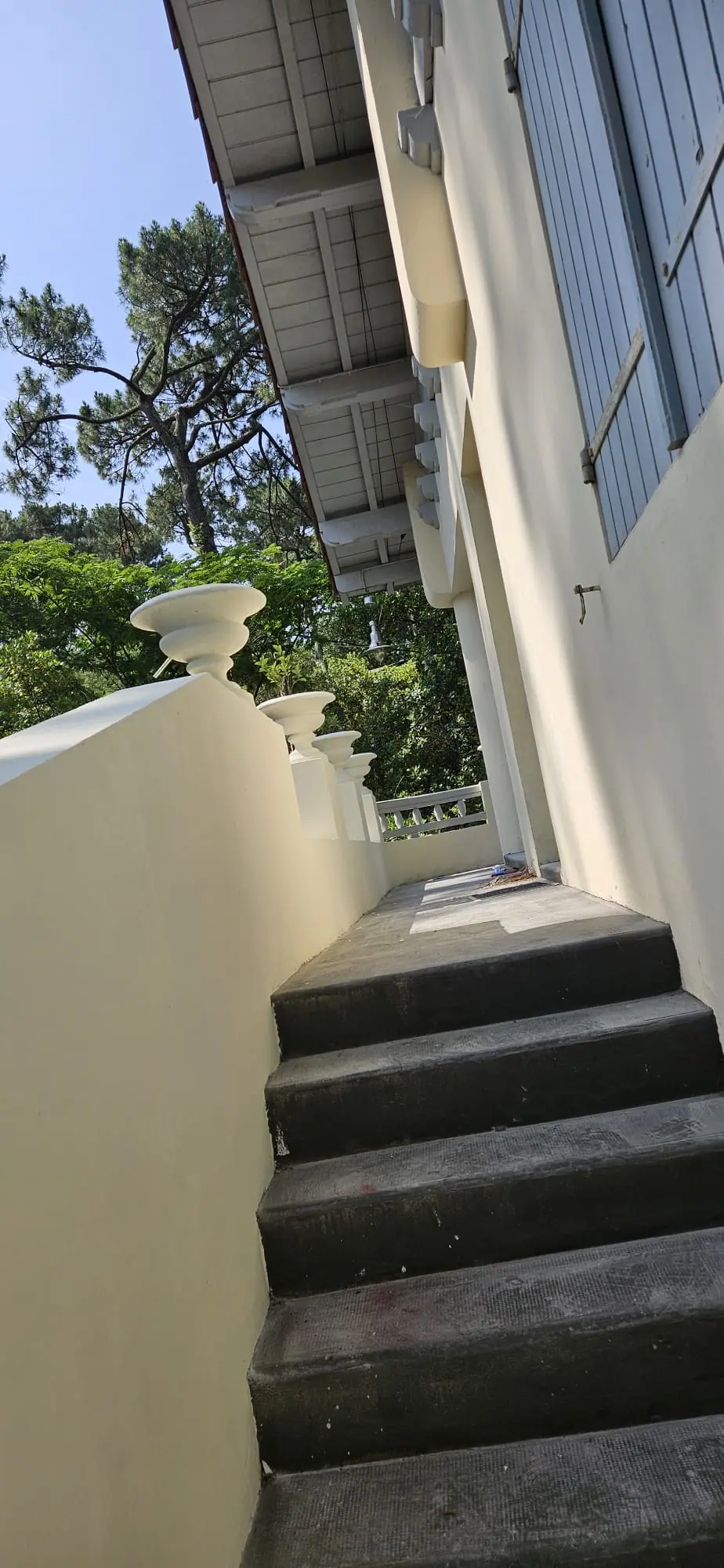 Association de couleurs sur une villa : murs, murets et vasques crème, volets gris