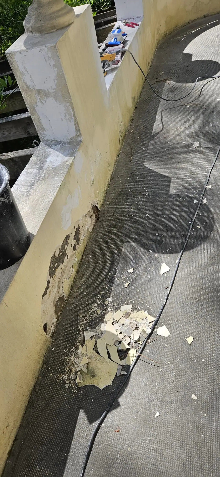 Avant : murets de la villa à l’ancienne peinture jaunie et écaillée, en cours de grattage, écailles au sol